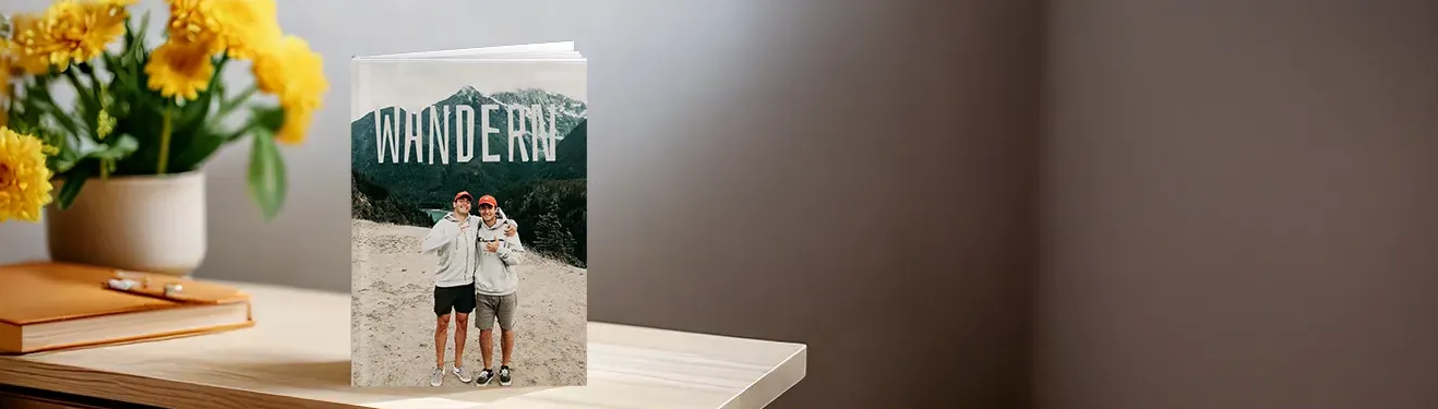 Ein aufgeschlagenes Fotobuch mit fröhlichen Momentaufnahmen. Haltet eure schönsten Fotos in einem Fotobuch fest.