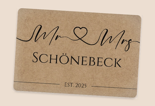 Braune Fußmatte als Fotogeschenk zur Hochzeit. mit Text 'Mr Mrs SCHÖNEBECK EST. 2025', dekorativ verbunden durch eine Herzlinie