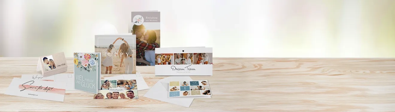 Verschiedene personalisierte Grußkarten mit Familienmotiven auf einem hellen Holztisch. Gestaltet hier Karten mit euren Fotos!