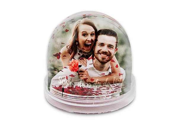 Eine mit Foto, Wasser und Flocken gefüllte, runde Schneekugel aus transparentem Hartplastik.