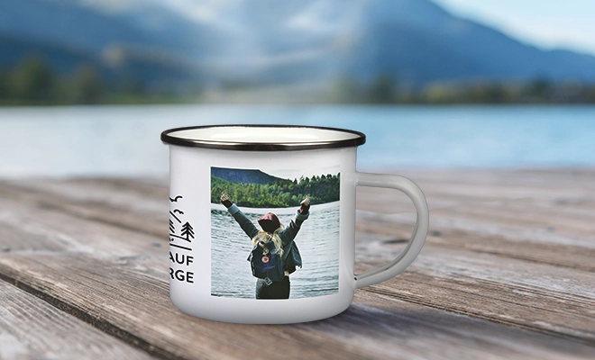 Weiße Emailletasse mit Foto und dekorativem Design, platziert auf einem Holzsteg