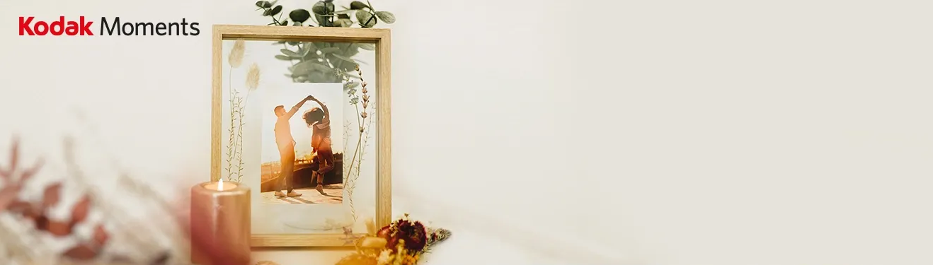 Ein dekorativer Holzrahmen mit einem Foto von tanzenden Personen, umgeben von Trockenblumen.