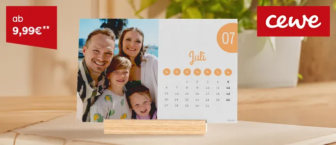 Ein Kalender mit winterlichem Foto hängt an einer Wand, umgeben von natürlicher Dekoration.