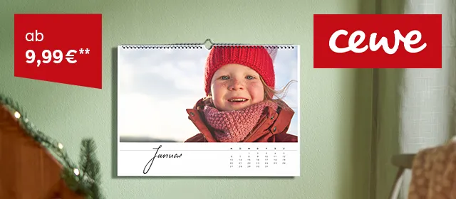 Wandkalender mit Kalendermonat Januar aufgehängt an grüner Wohnwand. Daruf ein Foto mit Kind und rotem Winteranzug, Mütze und Schal