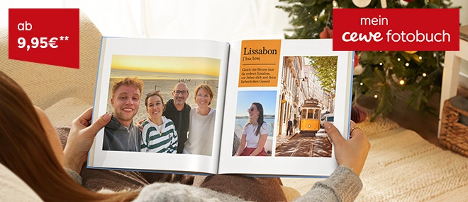 Frau sitzt im weihnachtlich geschmücktem Raum und sieht sich Fotobuch an. Aufgeschlagene Seite zeigt verschiedene Urlaubsbilder