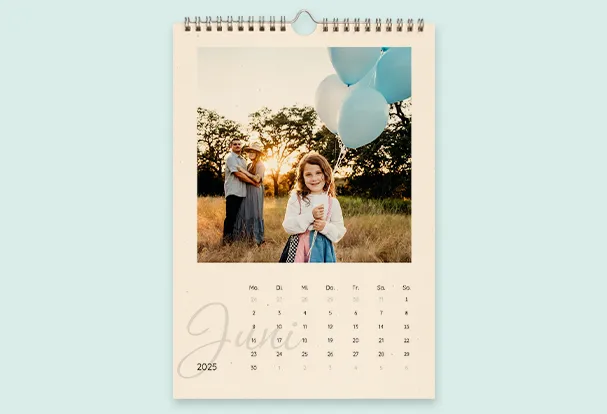 Personalisierter Wandkalender mit Spiralbindung, der ein Familienfoto und Monatsübersicht mit dekorativer Gestaltung zeigt.