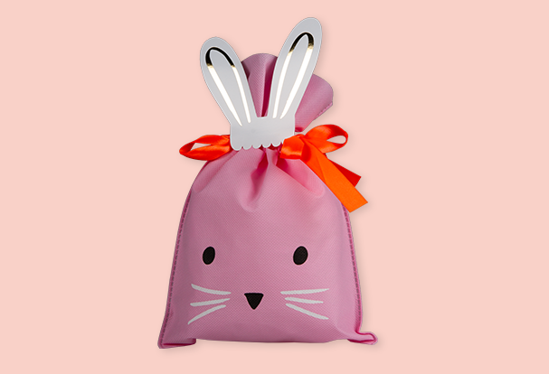 Persönliche Geschenke zu Ostern: Eine rosafarbene Geschenktüte in Hasenform mit Schleife für kleine Osterüberraschungen.