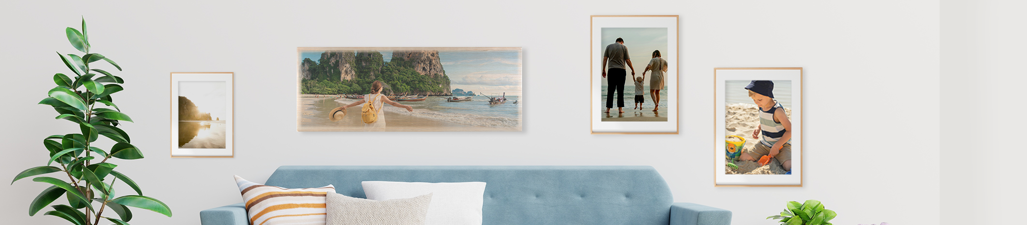Wohnzimmerszene mit unterschiedlichen Wandbildern, über blauer Couch großes Foto auf Holz, links und rechts daneben gerahmte Poster, Mehrteilige Leinwand auf der rechten Seite mit Strandmotiv
