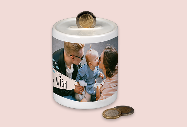 Eine weiße Spardose mit persönlichem Familienfoto und einem Münzschlitz auf dem Deckel, dekoriert mit Münzen.