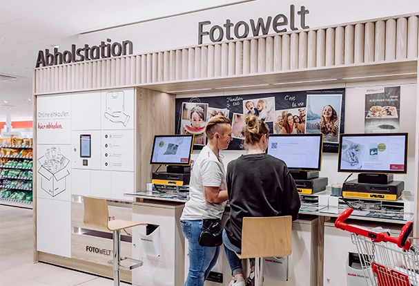 Kundinnen nutzen eine Foto-Station in der ROSSMANN Filiale