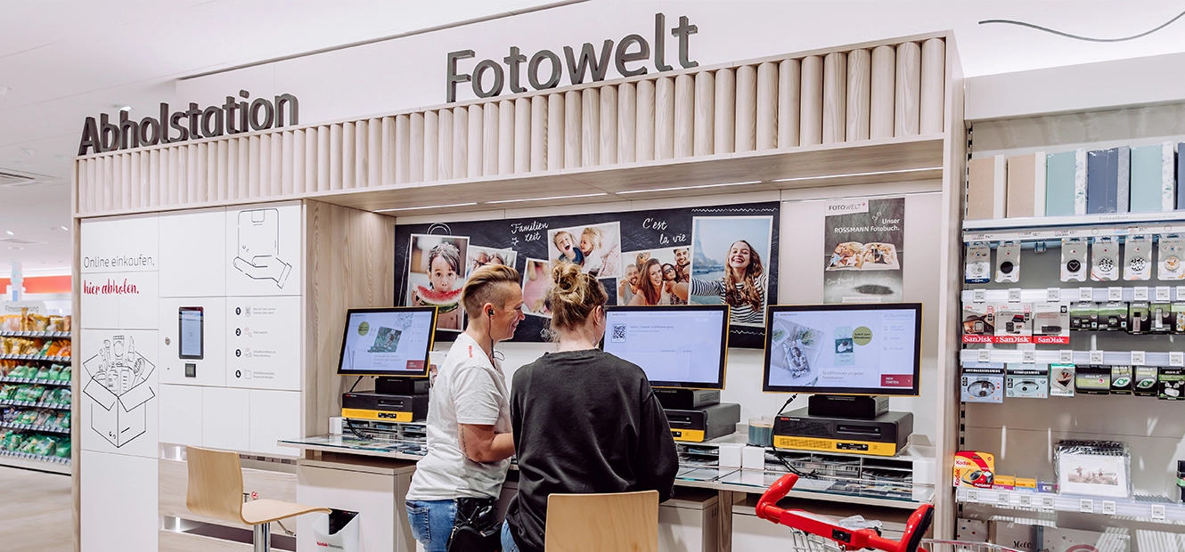 Kundinnen nutzen eine Foto-Station in der ROSSMANN Filiale zur Fotobestellung