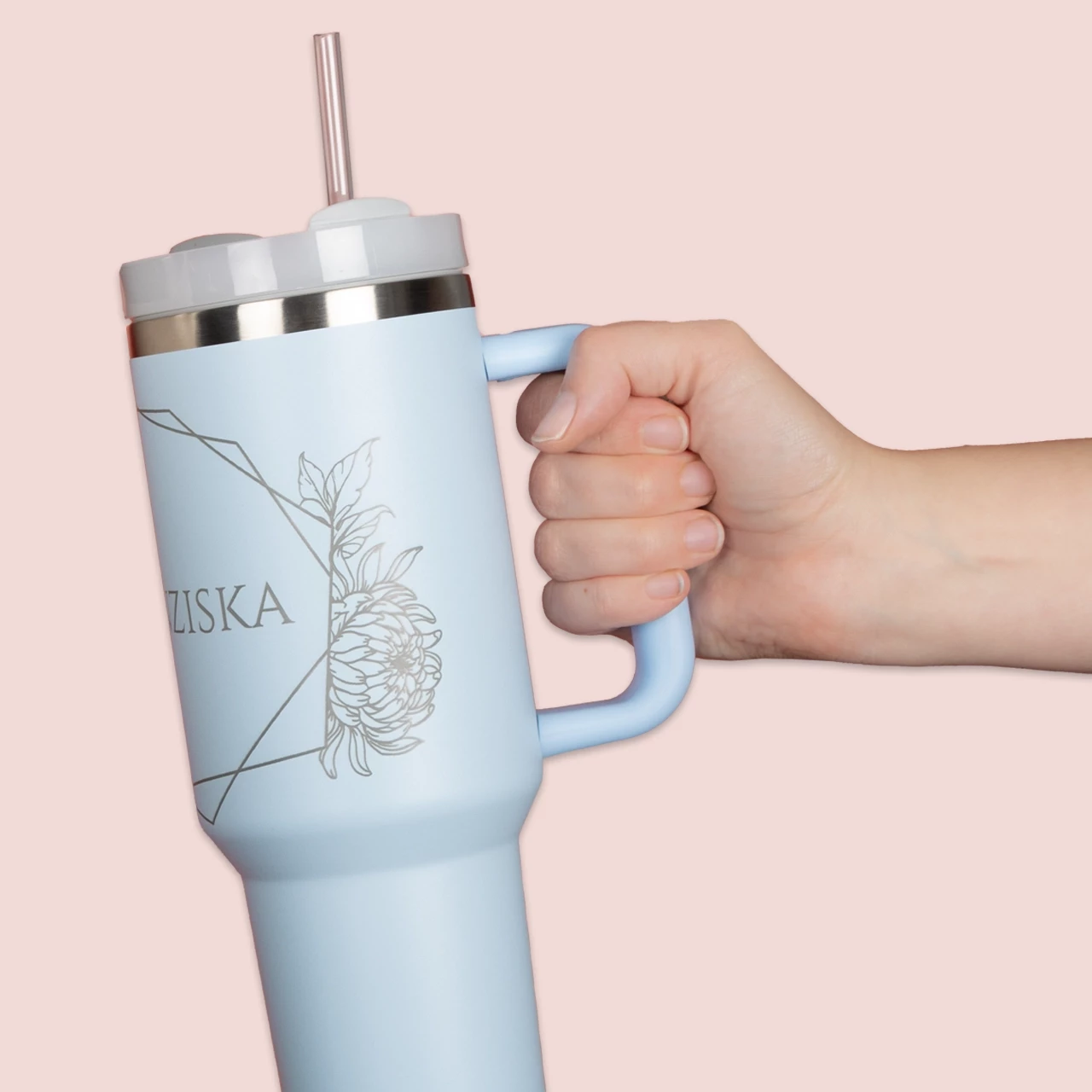 Ein pastellblauer Thermobecher mit Strohhalm und filigranem Blumendesign, personalisiert für Heiß- und Kaltgetränke unterwegs.