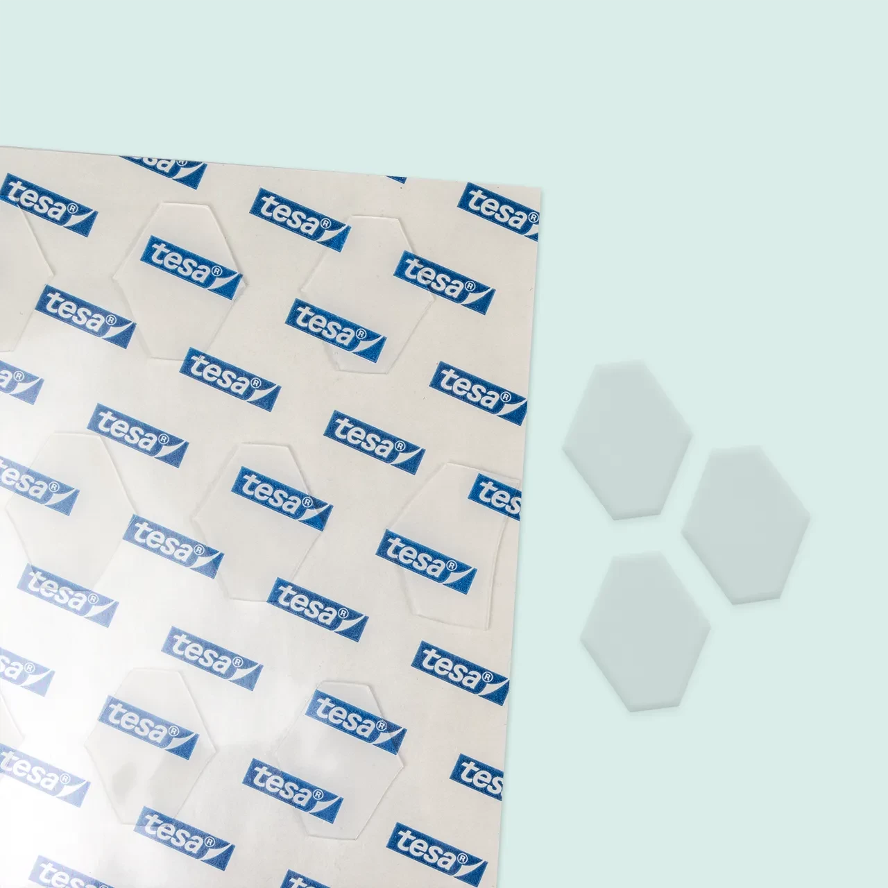 Detailansicht der tesa® Tack Klebefläche mit Logo-Muster und den hexagonalen Klebepads als Einzelteile.