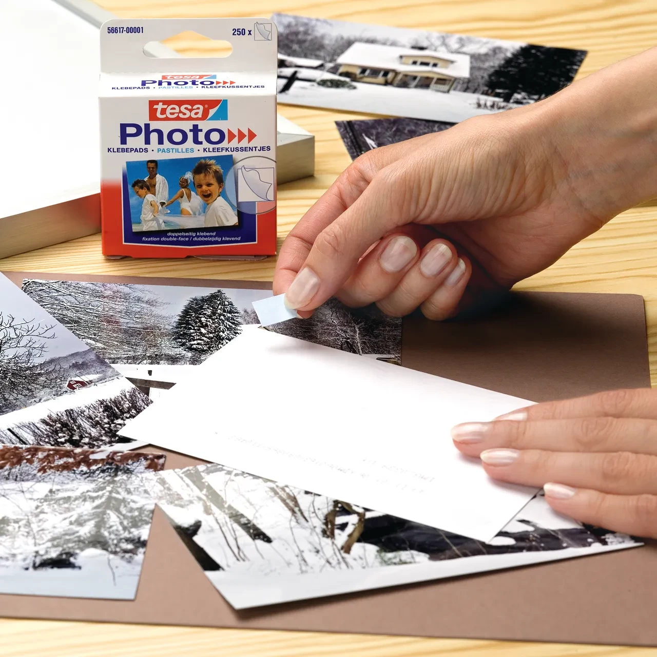 Anwendung von tesa® Photo Klebepads bei der Befestigung von Fotos auf einer Kartonoberfläche mit einfacher Handhabung.