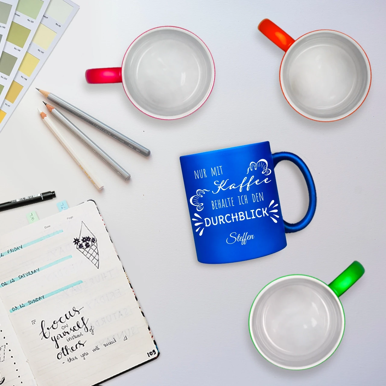 Eine Tasse gravieren lassen mit dem Spruch 'Nur mit Kaffee behalte ich den Durchblick', abgebildet auf einem Schreibtisch.